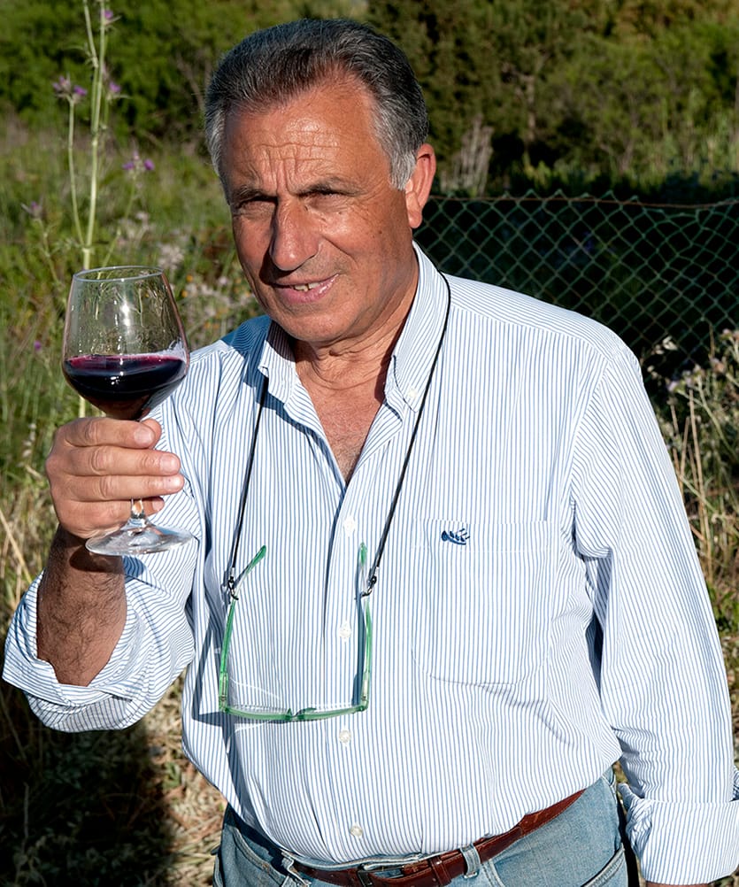 uomo in camicia sorridente con un bicchiere di vino in mano